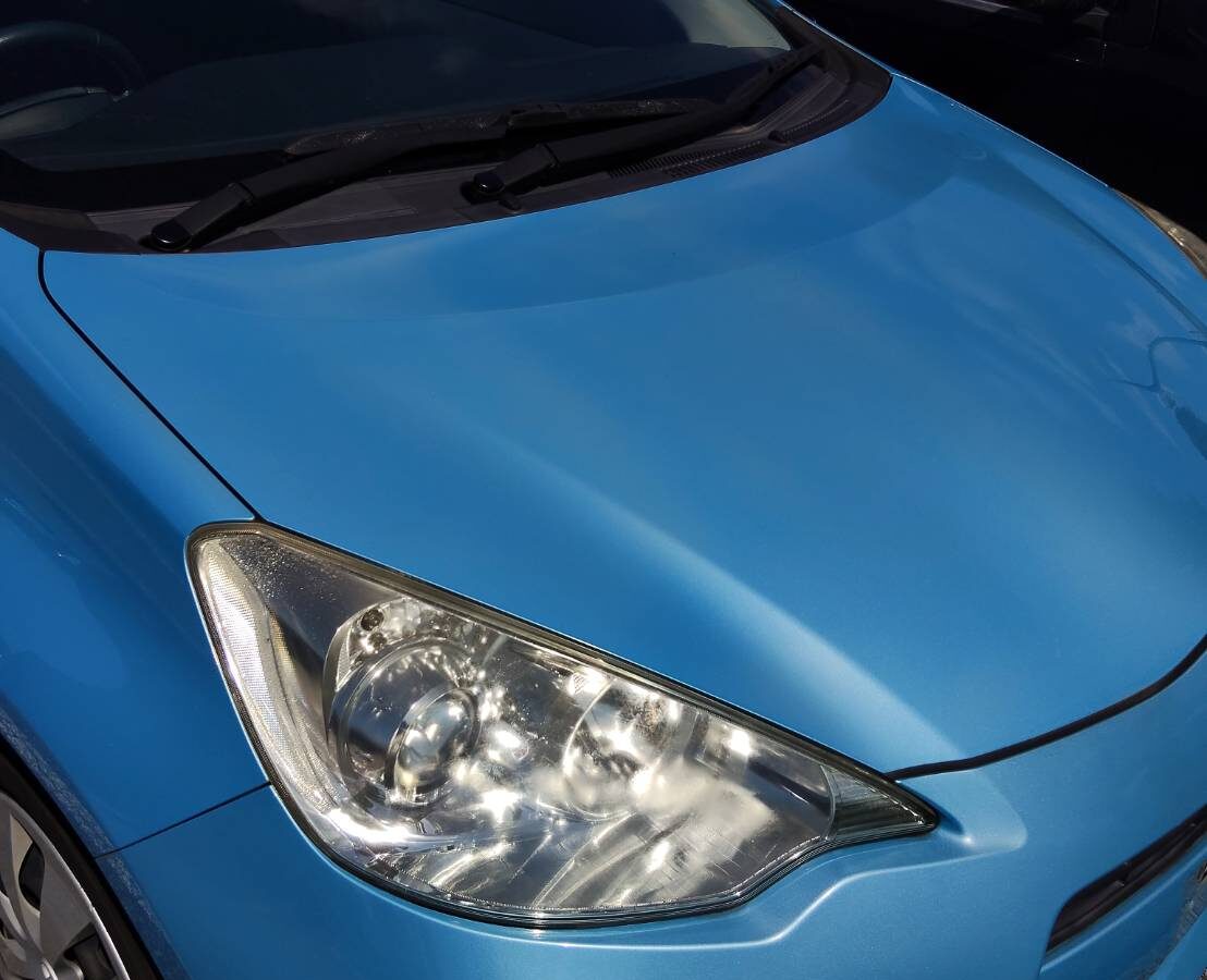 Front of a light blue Toyota Aqua: bonnet and right headlight